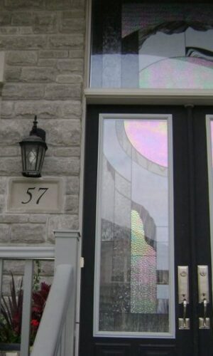 Custom Door Glass Insert in modern front door, abstract stained glass, stone wall, house number 57, black lantern.