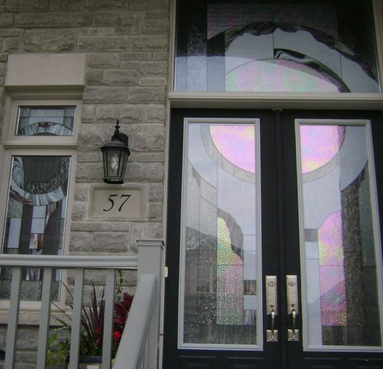 Custom Door Glass Insert in modern front door, abstract stained glass, stone wall, house number 57, black lantern.