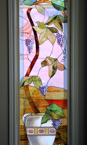 Grape Tree Vine Stained Glass with green leaves, purple grapes, and a white vase on a pastel background.
