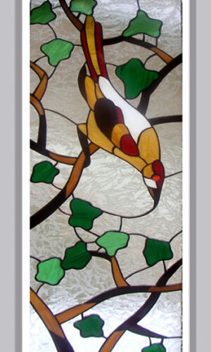 Bird on a Branch Stained Glass panel features a bird with yellow, white, red plumage perched on green-leaved branches.