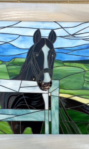 Stained glass horse artwork shows a black horse behind a fence with green and blue countryside background.