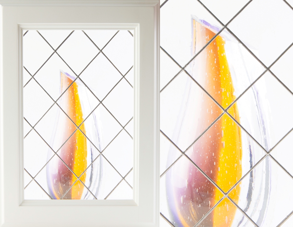 Tall yellow Apollo sculpture reflected in a white-framed mirror, set against a tiled background.
