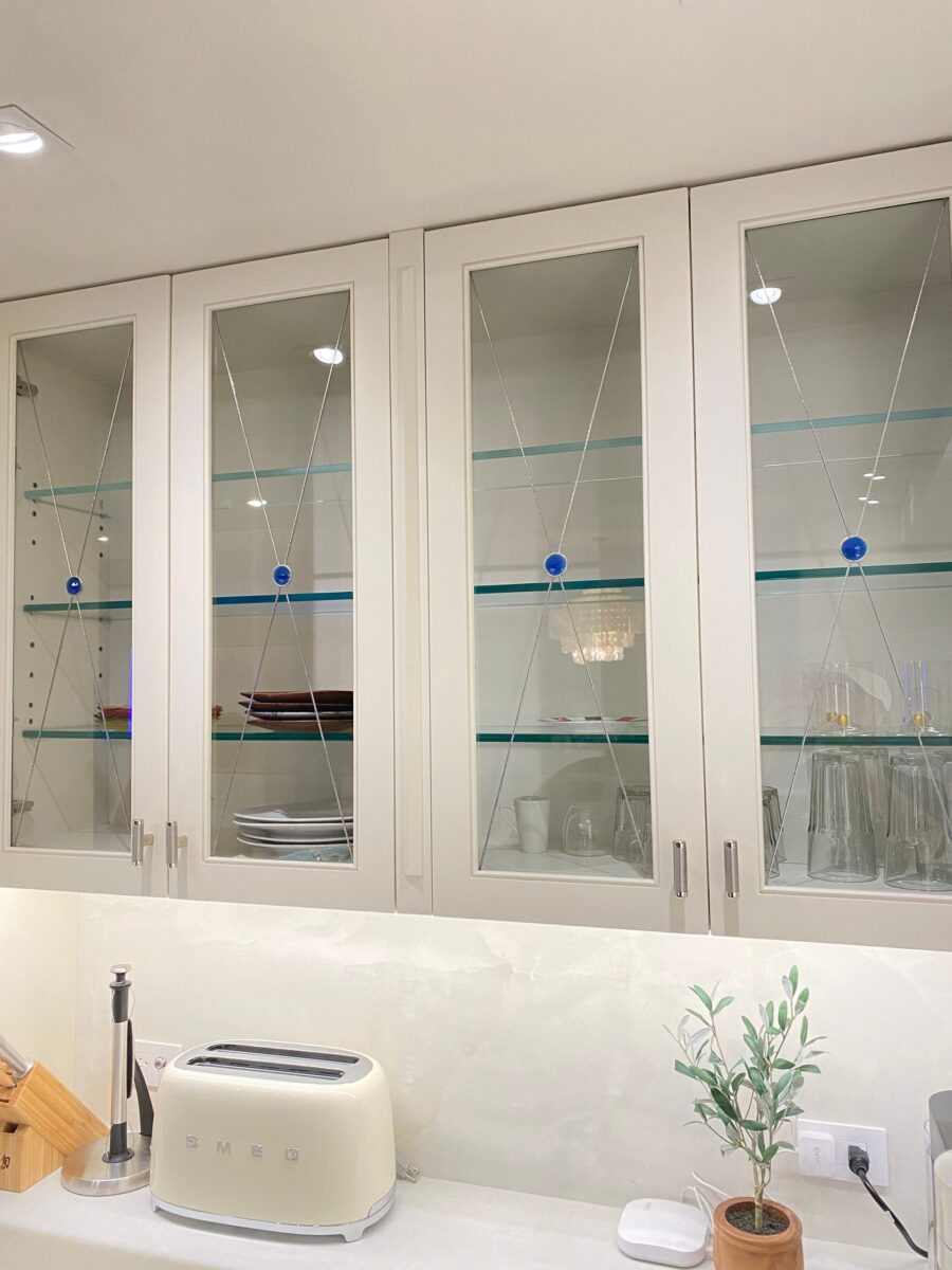 Chester cabinets with glass inserts showcase dishes; a toaster and plant rest on the counter below.