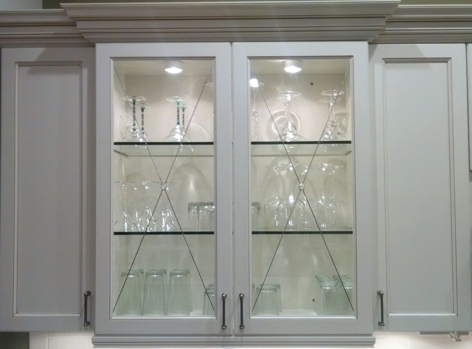 Chester glass-front cabinet with shelves and inserts, displaying clear stemware, beautifully lit from above.