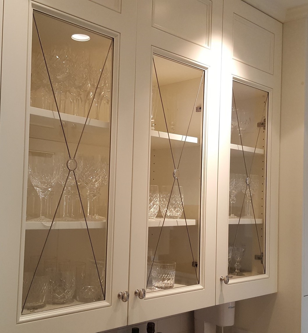 Chester glass-front cabinets with inserts display crystal glassware like wine glasses and tumblers.