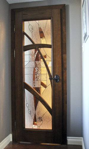 Custom Stained Glass Door Insert with abstract curved, textured glass in a wooden hallway door.
