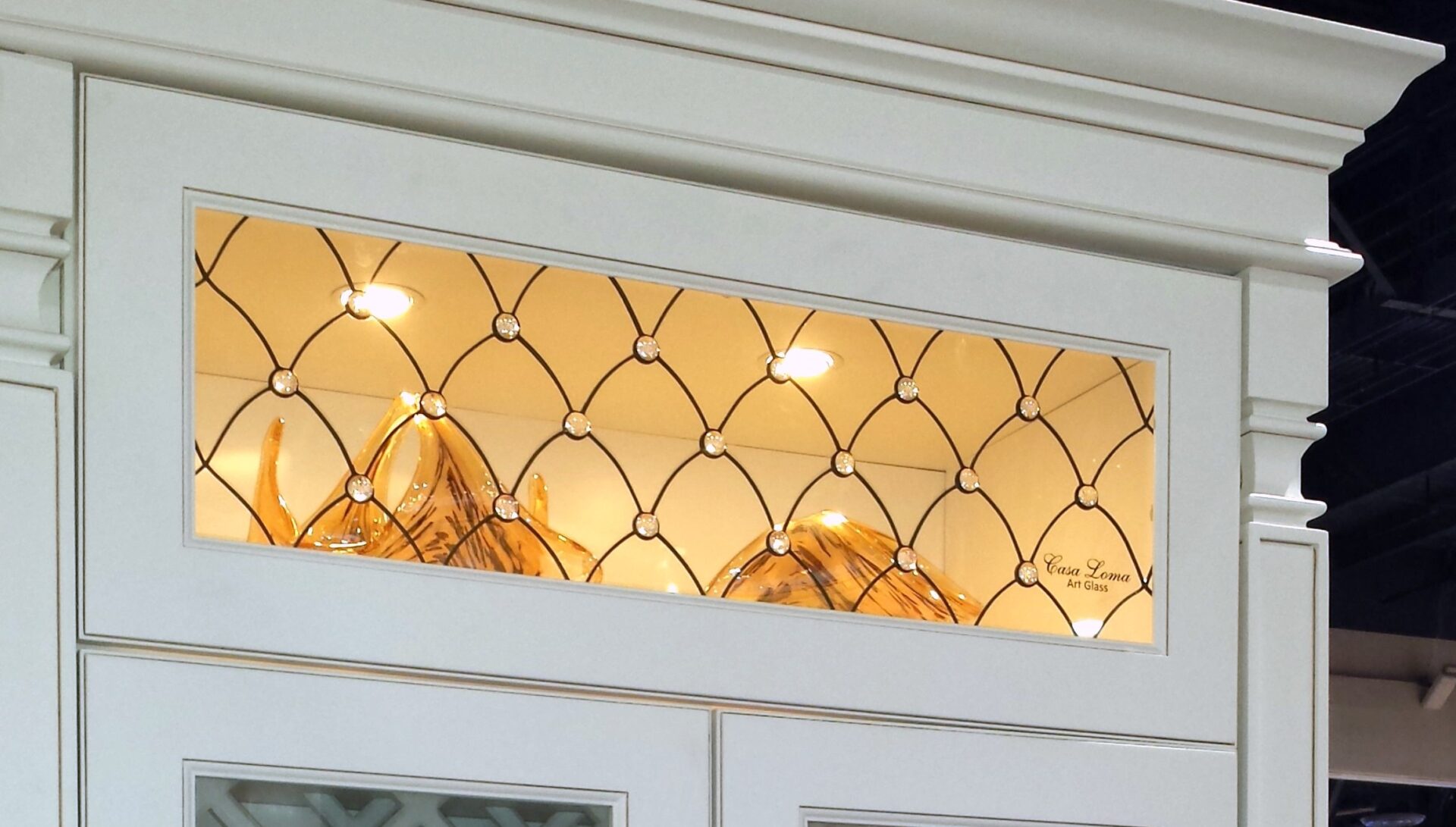 Venezzia cabinet features glass-front display, unique art glass, interior lighting, and decorative accents inside.