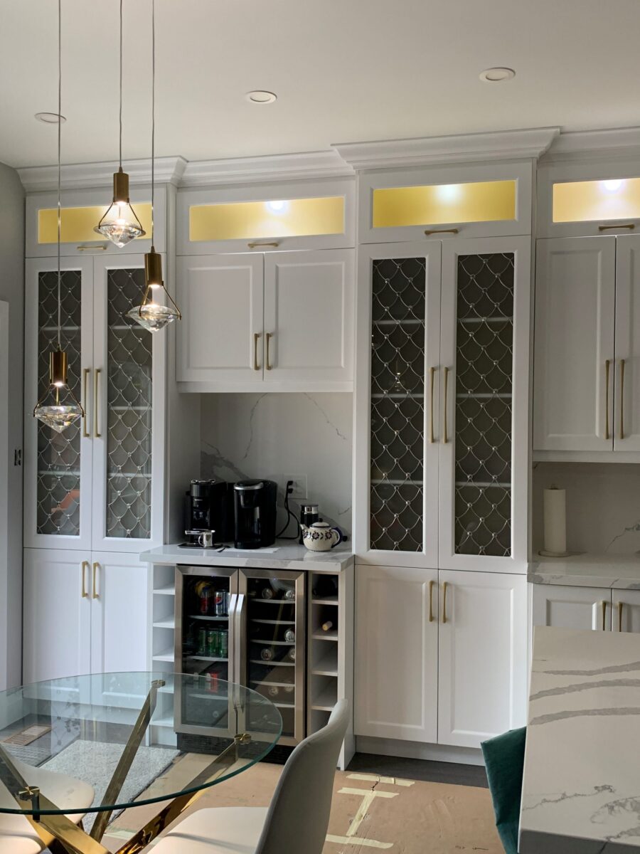 Modern kitchen with Venezzia white cabinets, art glass doors, pendant lights, and a coffee station.