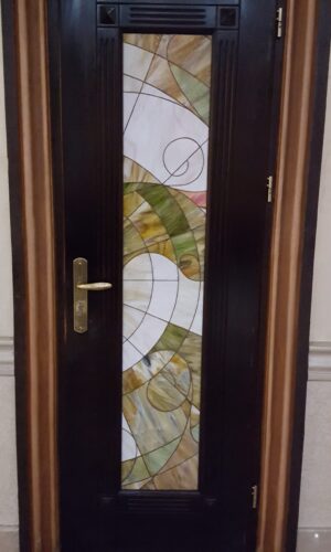 Custom Stained Glass Door Insert: Dark wood door with a vertical panel in abstract green, yellow, and white.