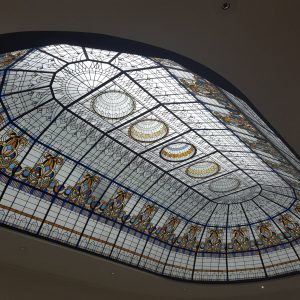 This is a stained glass ceiling with intricate blue, yellow, and white patterns, likely from an ornate or historic building.