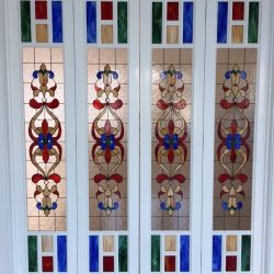 Four white-framed doors with decorative stained glass panels in red, blue, green, and tan geometric patterns.