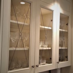 Glass-front kitchen cabinets with shelves displaying various crystal glasses and glassware.
