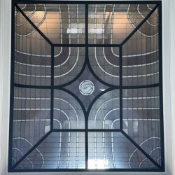Decorative glass ceiling with geometric black grid pattern and curved frosted glass panels in a white frame.