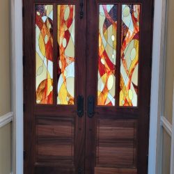Double wooden doors with colorful stained glass panels featuring abstract red, yellow, and white patterns.