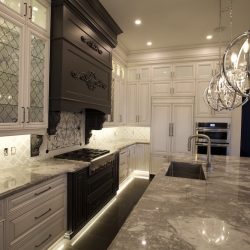 Modern kitchen with marble countertops, white cabinets, stainless appliances, and pendant lights over the island.