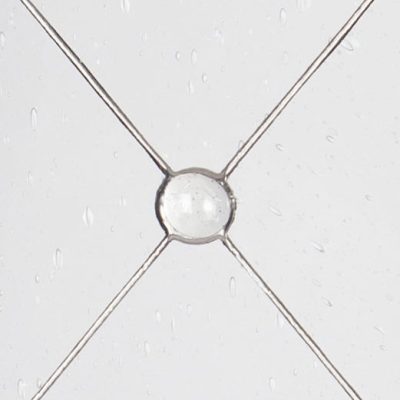 Close-up of a glass pane with raindrops, intersected by metal wires forming a diamond pattern.