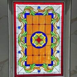 Rectangular stained glass window with colorful geometric and floral patterns in red, blue, green, and yellow tones.