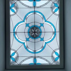 Rectangular stained glass window with blue and clear geometric floral pattern, framed by a white border.