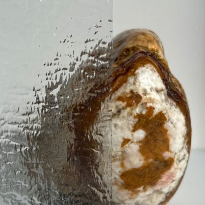 Piece of textured glass partially obscures a brown and white rock, with a Casa Loma Art Glass logo in the top right corner.