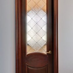 Closed wooden door with frosted glass panel featuring a diamond pattern, set in a plain, light-colored wall.