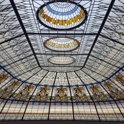 Stained glass ceiling with geometric patterns, blue and yellow accents, and circular designs in the center.