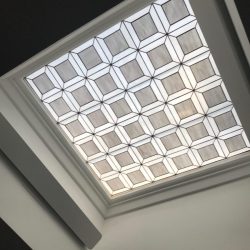 A skylight with a geometric, grid-patterned frosted glass design set in a white ceiling.