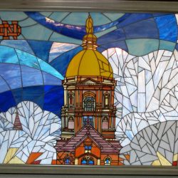 Stained glass artwork depicting a domed building with blue and white sky background and an “ND” logo in the corner.